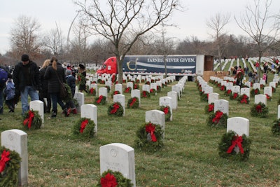 Volunteers place wreaths that were delivered by Bay & Bay Transportation, who decorated their trailer to honor the United States Marine Corps.