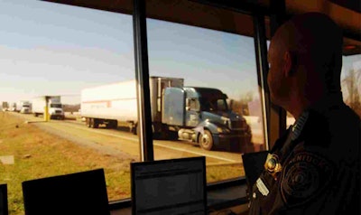 Man inside a weigh station as trucks drive by