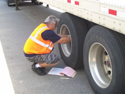 truck driver checking a truck tire