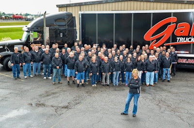 Sherri Brumbaugh, front, stands with Garner employees in front of one of the company’s tractor-trailers.