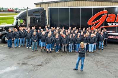 Sherri Brumbaugh, front, stands with Garner employees in front of one of the company’s tractor-trailers.
