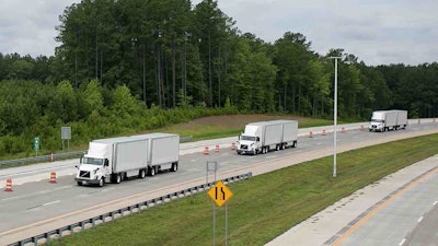 Three Volvo VNL trucks in a platoon along North Carolina highway 540.