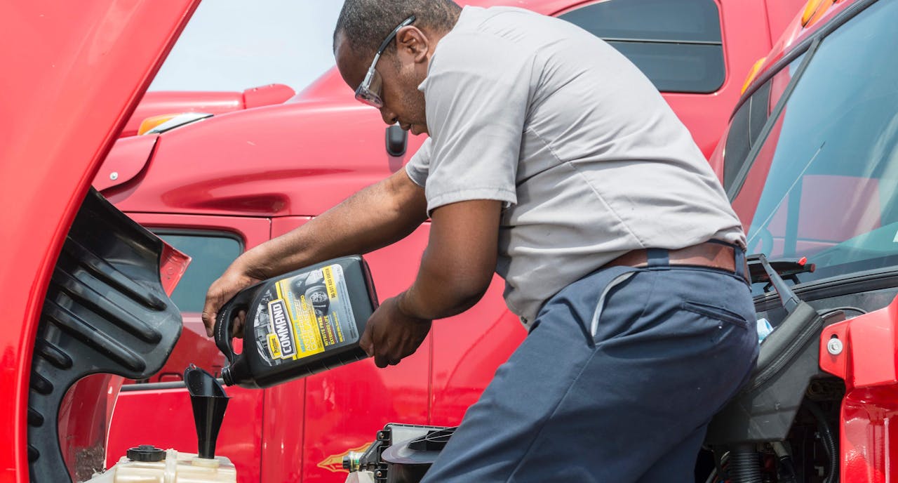 Man pouring fluid into a semi-truck