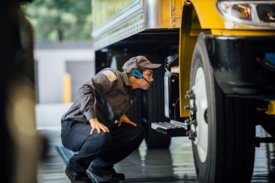 A Penske Truck Leasing technician logs into the hands-free voice-directed PM system on a Honeywell Talkman mobile device connected to a headset via Bluetooth. The system downloads the criteria for the specific vehicle the technician is inspecting.