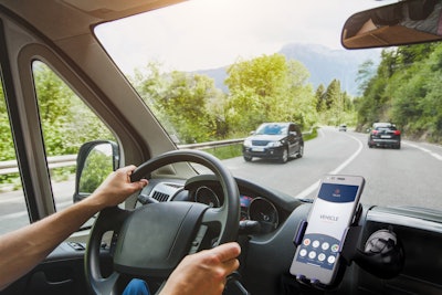 Trucker driving on road with phone in holder