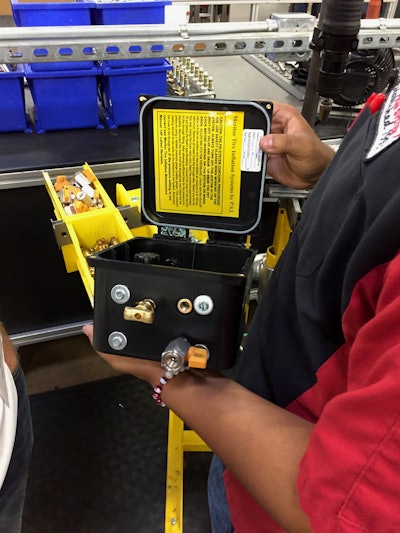 A PSI employee holds a Meritor Tire Inflation System that was just produced minutes before in PSI’s San Antonio factory.