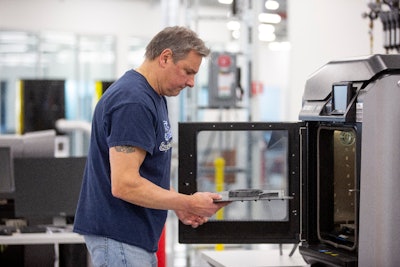 Dave Jacek, 3D printing technician, unloads 3D printed medical face shield parts at Ford’s Advanced Manufacturing Center. Ford Motor Company, joining forces with firms including 3M and GE Healthcare, is lending its manufacturing and engineering expertise to quickly expand production of urgently needed medical equipment and supplies for healthcare workers, first responders and patients fighting coronavirus. (photo courtesy of Ford)