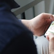 Cropped shot view of man hands holding smart phone with blank copy space screen for your text message or information content, female reading text message on cell telephone during in urban setting.