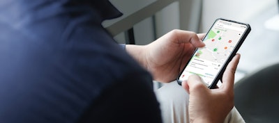 Cropped shot view of man hands holding smart phone with blank copy space screen for your text message or information content, female reading text message on cell telephone during in urban setting.