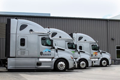 Three semi-truck tractors in front of a metal building