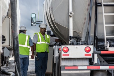 Two people in safety vests and hardhats standing between trucks in New Mexico