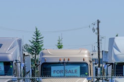three white semi-trucks parked in a row with for sale signs in their front windows
