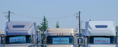 three white semi-trucks parked in a row with for sale signs in their front windows