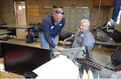 Two men discussing work over a laptop
