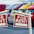 parked semi trucks with 'for rent' signs in front of them
