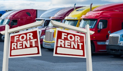 parked semi trucks with 'for rent' signs in front of them