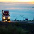 Semi-truck on empty highway at dusk