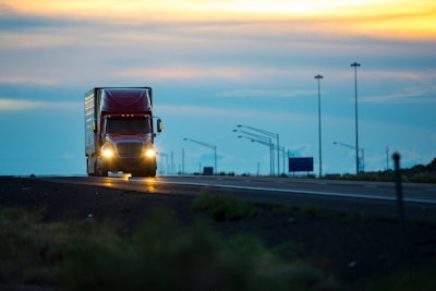 Semi-truck on empty highway at dusk