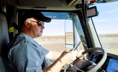 Truck driver behind the wheel looking at his phone