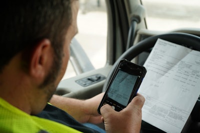 Truck driver using his phone to take a picture of his loading bill