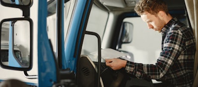 man looking over paperwork inside truck