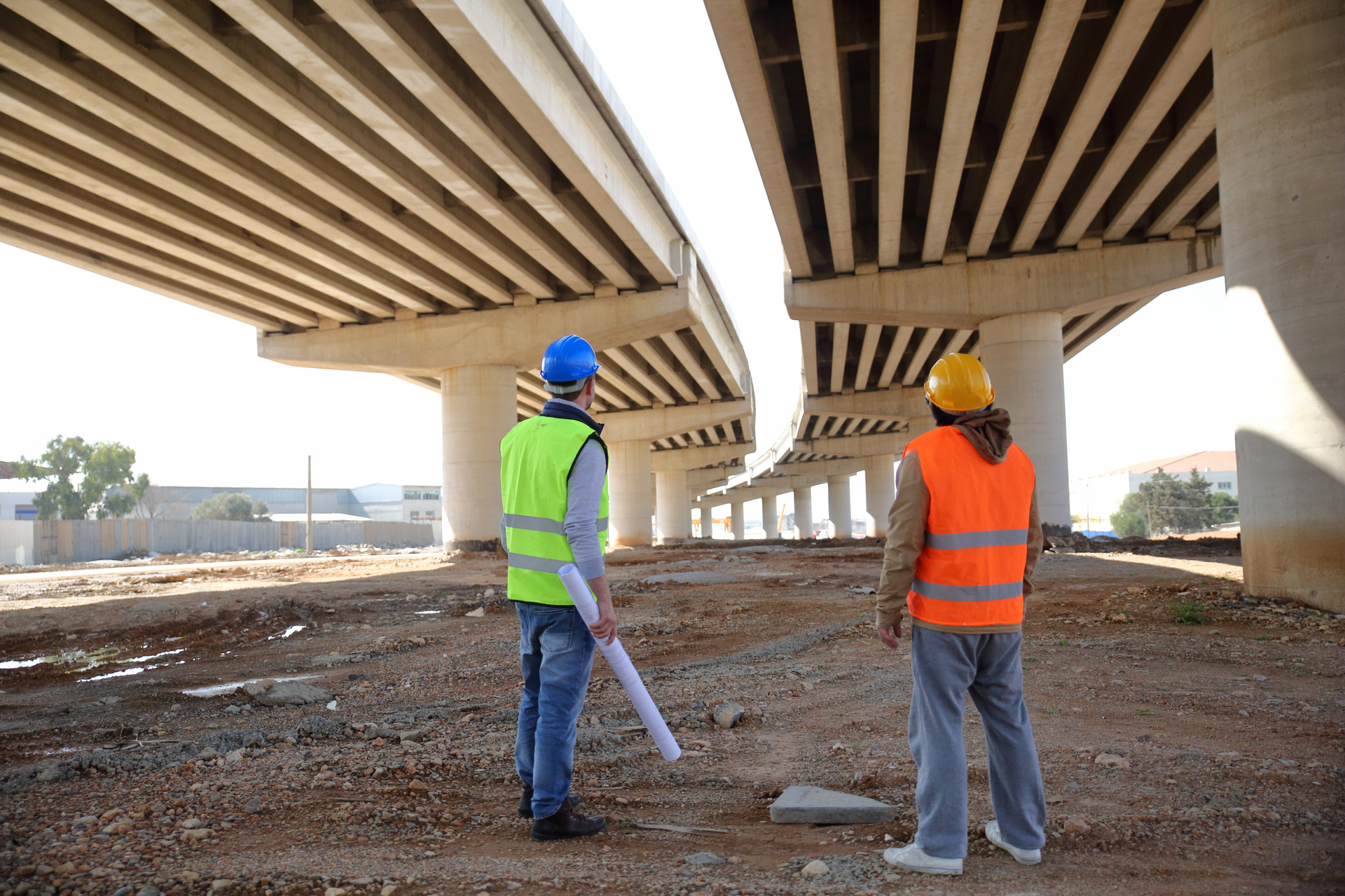 two construction workers working under bridge