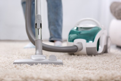 person using vacuum cleaner on carpet