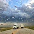 semi-trucks driving on a highway during a rainstorm