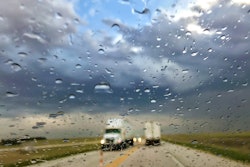 semi-trucks driving on a highway during a rainstorm