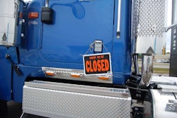 sorry we're closed sign hanging on a semi-truck's door