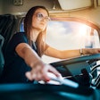 A young, female driver behind the wheel of a truck.
