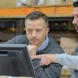 Employees looking at computer monitor in warehouse