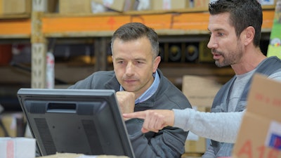 Employees looking at computer monitor in warehouse