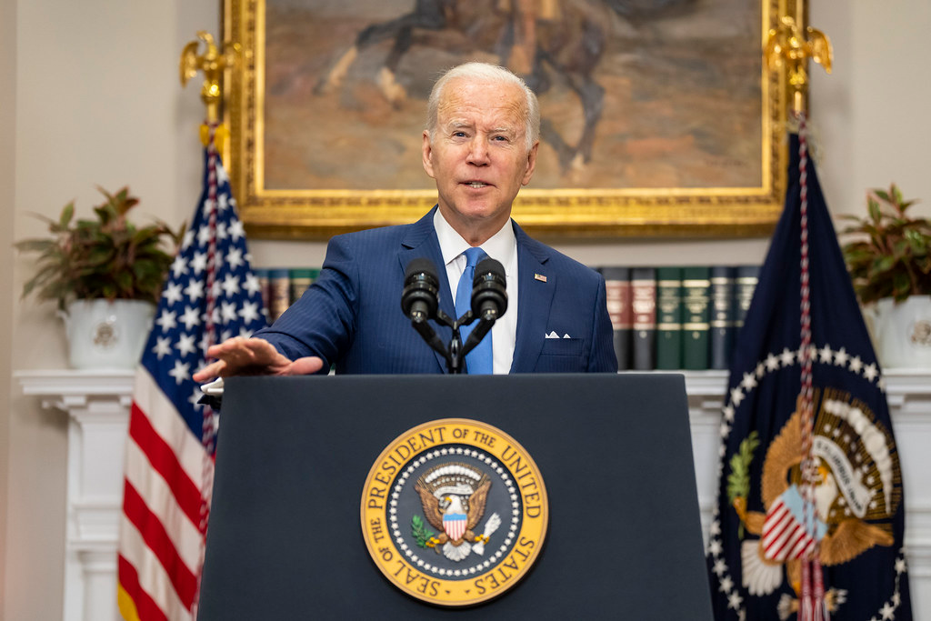 President Joe Biden speaking from a podium with the flag of the United States and the flag of the President of the United States in the background