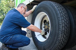 Transervice technician checking tire air pressure on a semi-truck