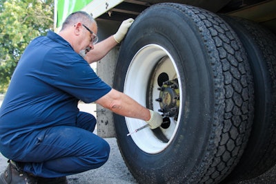 Transervice technician checking tire air pressure on a semi-truck