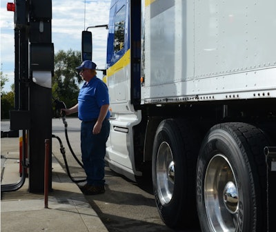 Driver fuels a truck at a diesel pump.