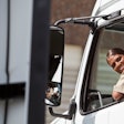 a female truck driver looking out of the driver's window of a semi-truck