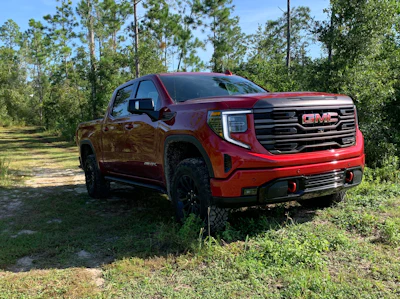 2022 GMC AT4X pickup truck red parked on dirt road in woods