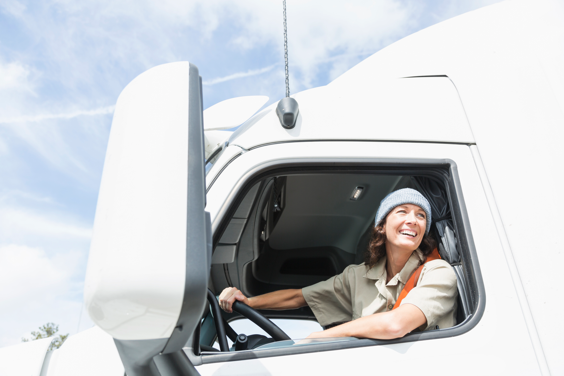 female truck driver behind the wheel of a semi-truck