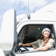 female truck driver behind the wheel of a semi-truck