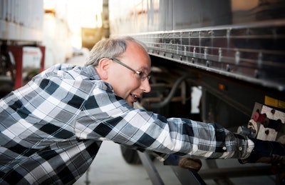 older driver inspecting a trailer