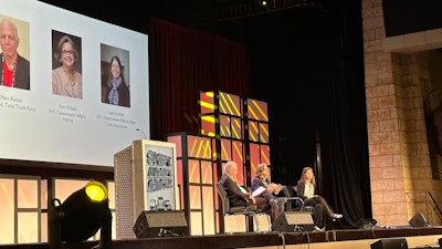 Three people on stage at a conference.