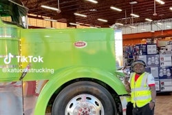 Joachim Wangui standing next to a lime green Peterbilt
