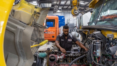 Technicians working on an engine in a truck shop