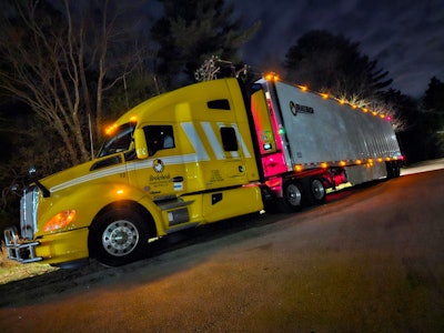 Brakebush Kenworth semi-truck at night with lights on