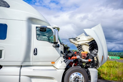 A white truck with the hood up for service under a partly cloudy blue sky.