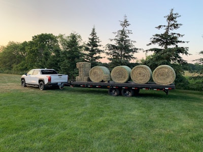 2024 Silverado EV Work Truck hauling a trailer loaded with hay bales in the shape of 10,000