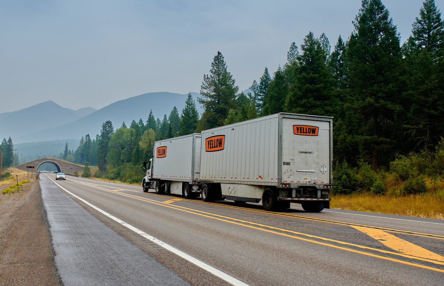 Yellow semi hauling dual pup trailers