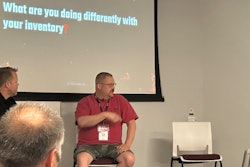 Two men sitting in front of a presentation screen.